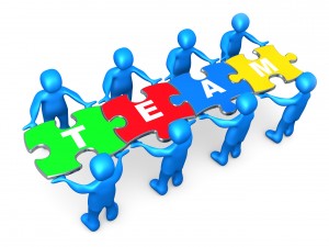 Team Of 8 Blue People Holding Up Connected Pieces To A Colorful Puzzle That Spells Out "Team," Symbolizing Excellent Teamwork, Success And Link Exchanging Clipart Illustration Graphic